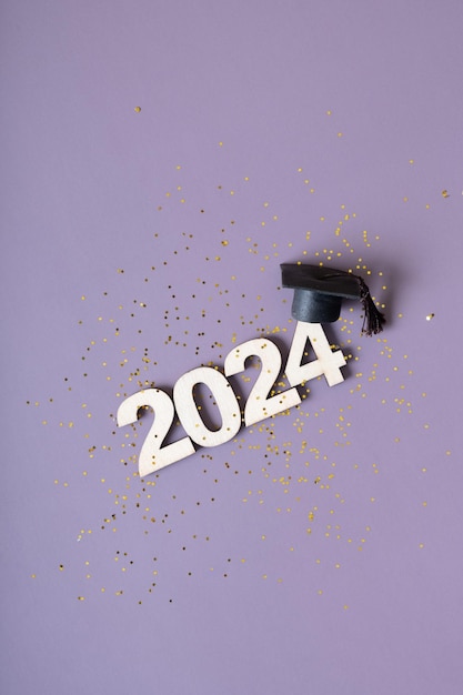 Class of 2024 concept Numero 2024 con tappo graduato e confetti su sfondo viola
