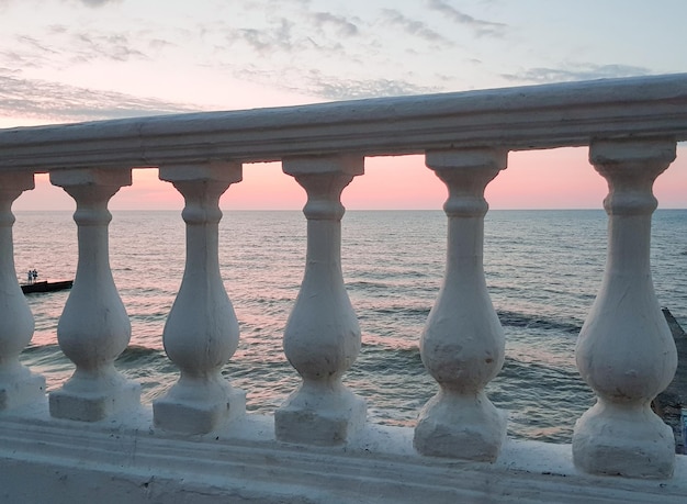 Classica balaustra in gesso bianco sullo sfondo di un mare calmo al tramonto - un delicato stato d'animo rosa