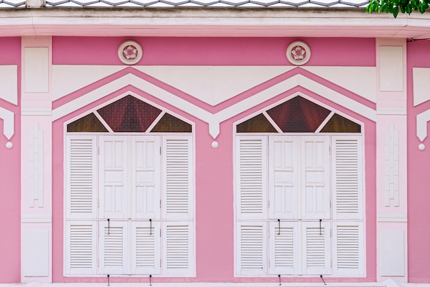 Classica finestra bianca e legno in un edificio di cemento rosa.