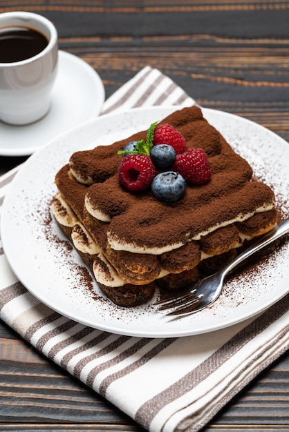 Classico dessert al tiramisù con lamponi, mirtilli e una tazza di caffè espresso