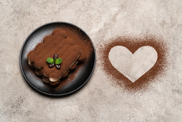 Classico dessert al tiramisù su piatto in ceramica e cacao a forma di cuore