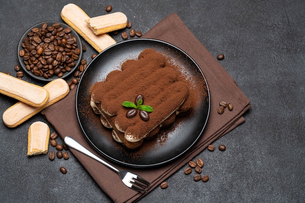 Classico dessert tiramisù e biscotti savoiardi su piatto in ceramica su tavola di cemento