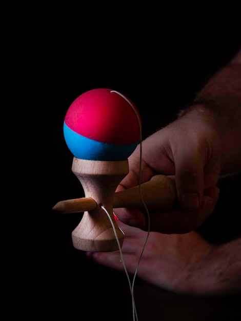 Classico gioco giapponese kendama su sfondo nero Due mani di ragazzi che giocano a kendama