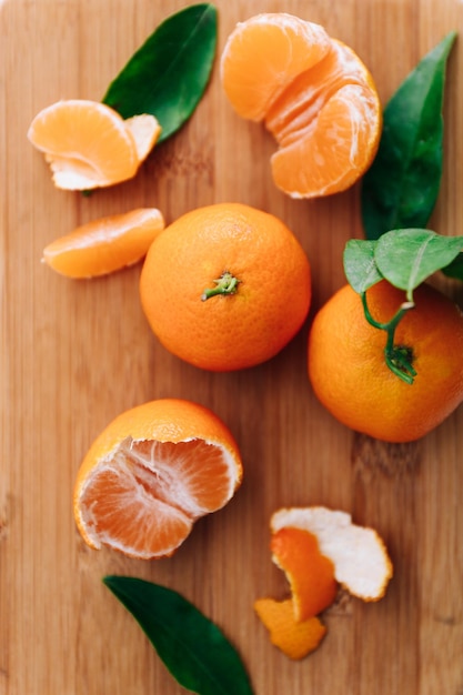 Clementine fresche con foglie su tavola di legno, vista dall'alto