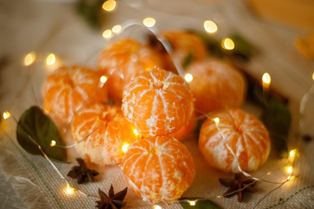 Clementine fresche o mandarini nel cesto sul tavolo di legno marrone con luci di Natale e rami di albero