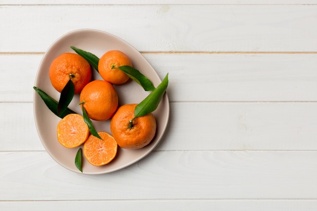 Clementine fresche tagliate e mandarino intero su piastra rotonda su sfondo colorato Ingredienti per cibi e bevande che preparano un'alimentazione sana tema vista dall'alto con spazio di copia