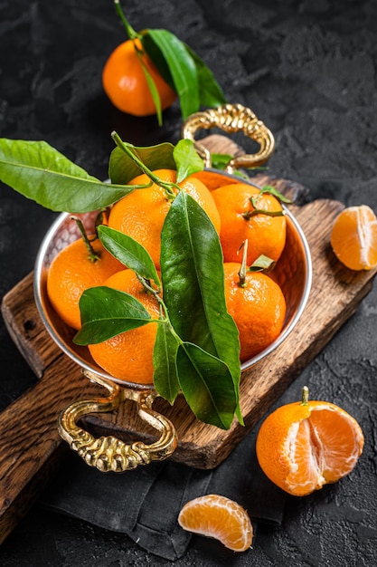 Clementine Mandarini con foglie verdi Sfondo nero Vista dall'alto