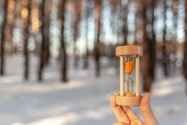 Clessidra come simbolo che cambia le stagioni neve che si scioglie Clessidra nella mano di una donna in inverno