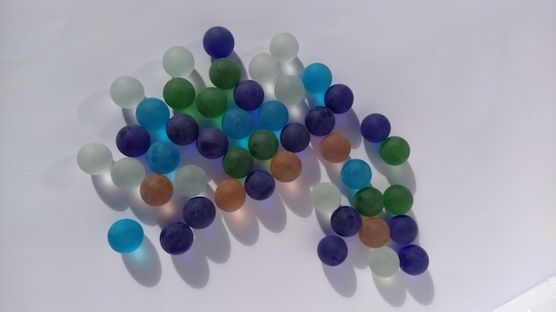 Clicker di gioco o palline di vetro colorato sparse su uno sfondo bianco retroilluminato
