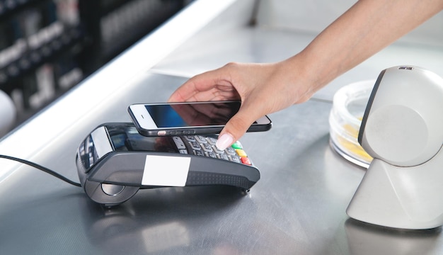 Cliente che paga per acquisti contactless con smartphone.