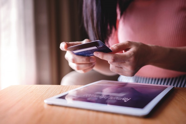 Cliente della donna che utilizza la carta di credito e il tablet per effettuare acquisti online