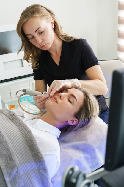 Cliente donna durante la pulizia profonda del viso in una clinica di cosmetologia