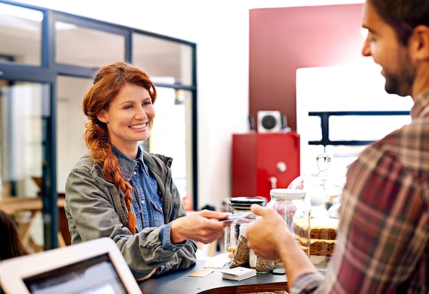 Cliente donna e carta di credito in un bar per il pagamento con un sorriso al ristorante Felicità della persona femminile e scansione automatica per pagare e acquistare in un bar con commesso e barista maschio