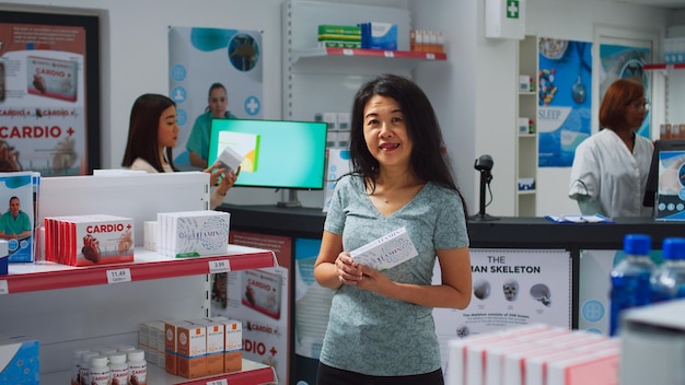 Cliente femminile alla ricerca di medicinali nel negozio di farmacia, guardando scaffali pieni di scatole di pillole e bottiglie. Cliente di farmacia che legge pacchetti di medicinali, prodotti farmaceutici.