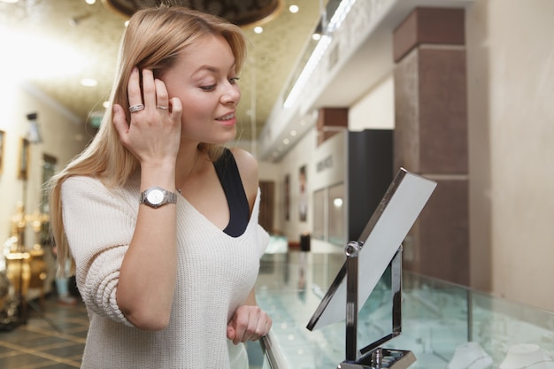 Cliente femminile attraente che prova sui gioielli al deposito