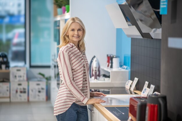 Cliente femminile biondo in piedi in uno showroom di beni di consumo e che sembra soddisfatto