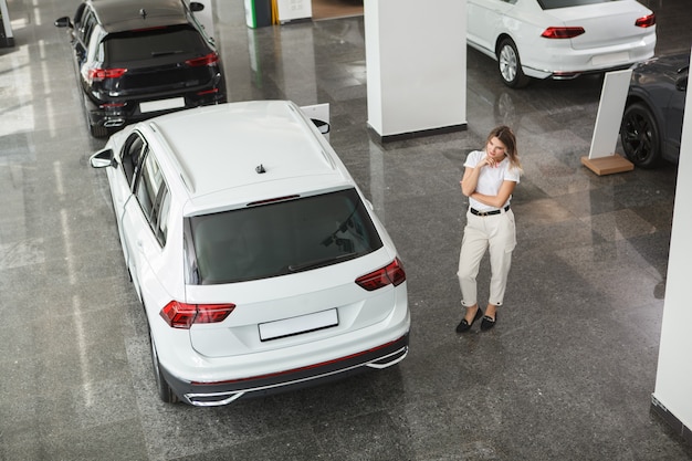 Cliente femminile che guarda una nuova auto SUV presso la concessionaria