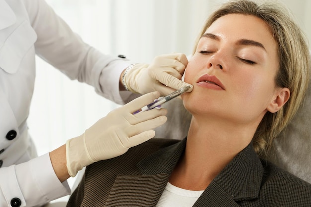 Cliente femminile durante le iniezioni di filler facciali in clinica medica estetica