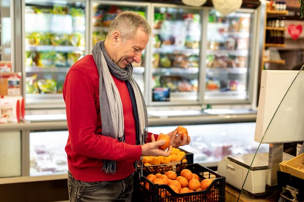 Cliente maschio che acquista al supermercato scegliendo il mandarino