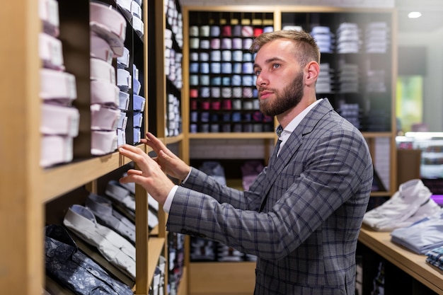 Cliente uomo alla ricerca di camicie classiche in un negozio d'élite