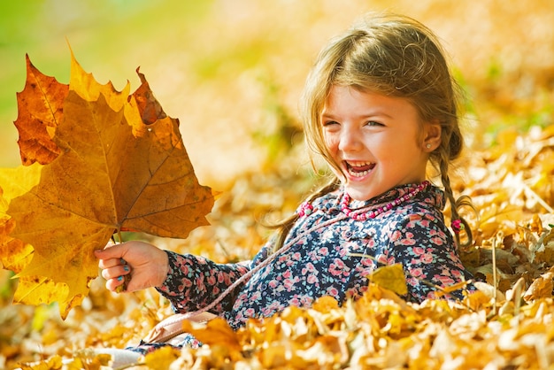 Clima caldo e soleggiato. Bambino sorridente su sfondo naturale autunnale. Giocando nel parco d'autunno. I bambini giocano all'aperto.