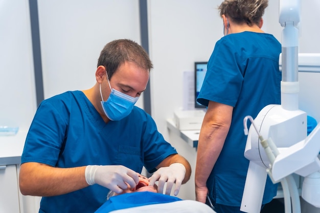 Clinica dentale dentista medico e assistente che esamina i denti di una donna anziana sdraiata sul tavolo