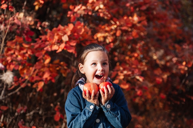 Close up autunno foresta concetto ragazza piuttosto deliziosa tenere grande mela rossa in mano con autunno ba...