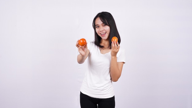 Close up belle donne asiatiche con un pomodoro isolato sulla superficie bianca