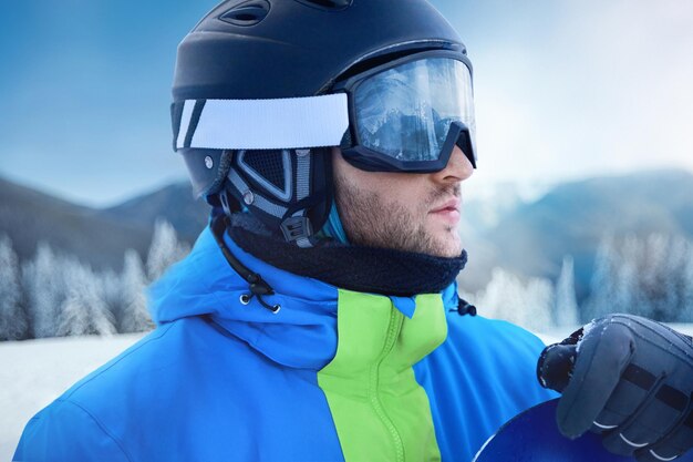 Close up degli occhiali da sci di un uomo con il riflesso di montagne innevate Una catena montuosa riflessa nella maschera da sci Ritratto di un uomo nella stazione sciistica sullo sfondo di montagne e cielo