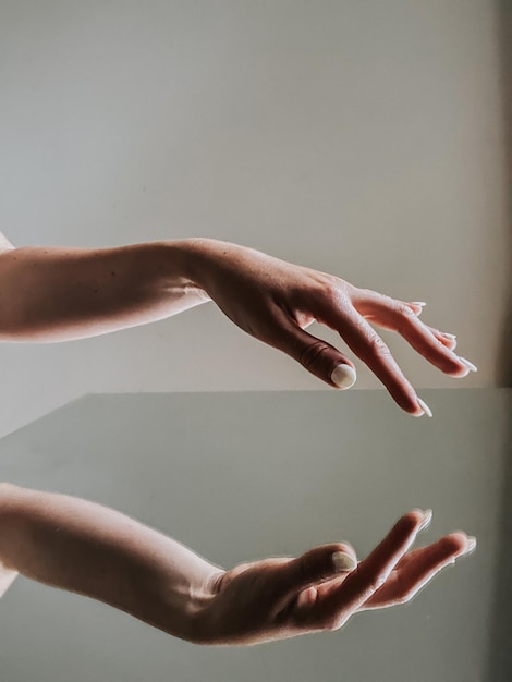 Close-up del riflesso della mano di una donna su uno sfondo bianco