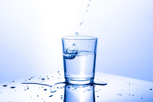 Close-up dell'acqua che spruzza sul vetro contro uno sfondo bianco