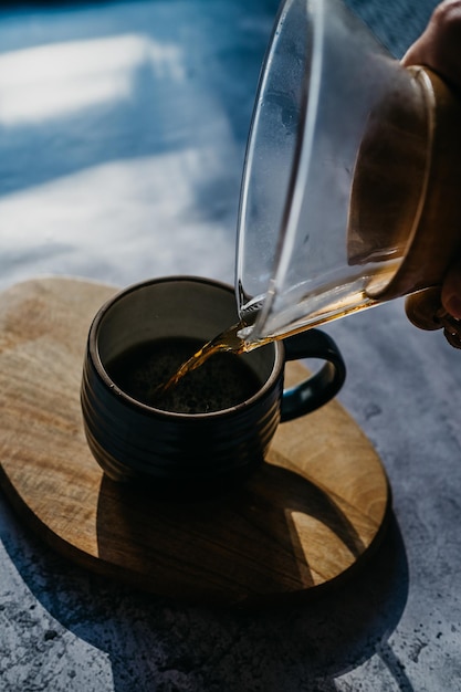 Close-up della mano che versa il caffè in una tazza sul tavolo