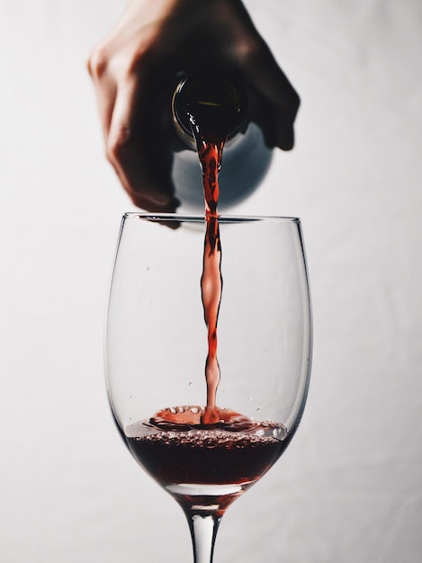 Close-up della mano che versa il vino nel bicchiere