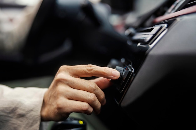 Close up della mano di una donna che accende la radio in un'auto
