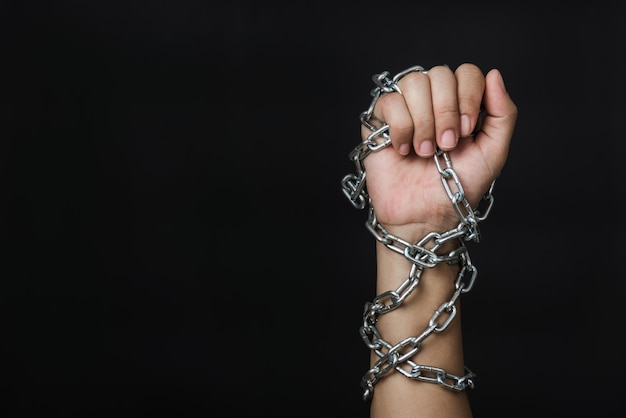 Close-up della mano di una donna che tiene gli occhiali su uno sfondo nero