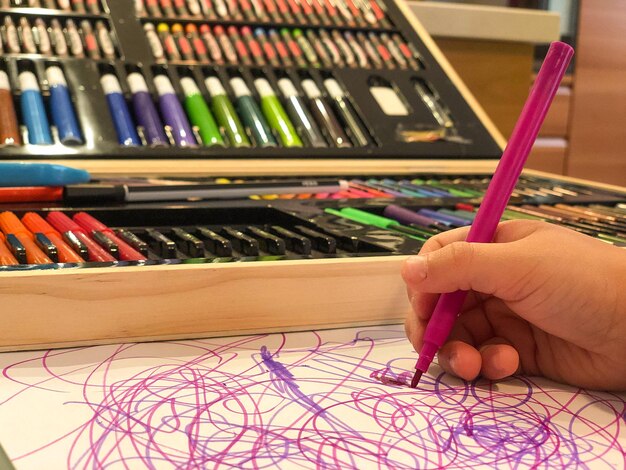 Close-up della mano di una ragazzina che scarabocchia su carta d'arte sul tavolo