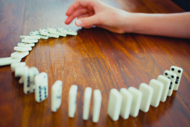 Close-up della mano umana che spinge il primo domino di fila