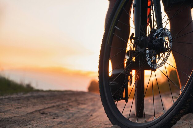 Close-up della ruota anteriore della bicicletta su un sentiero sullo sfondo del tramonto