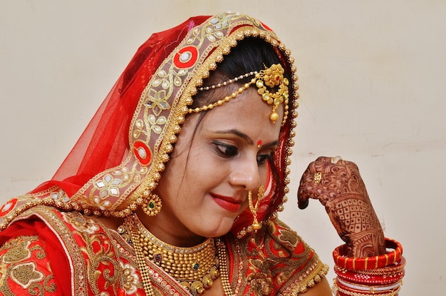 Close-up della sposa che indossa un sari rosso vicino al muro