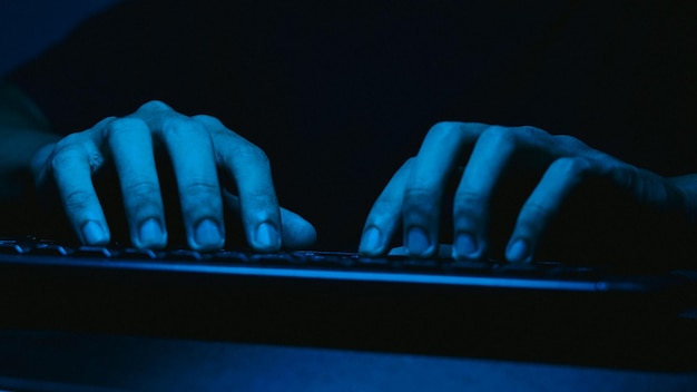 Close-up delle mani di un uomo che scrive su una tastiera