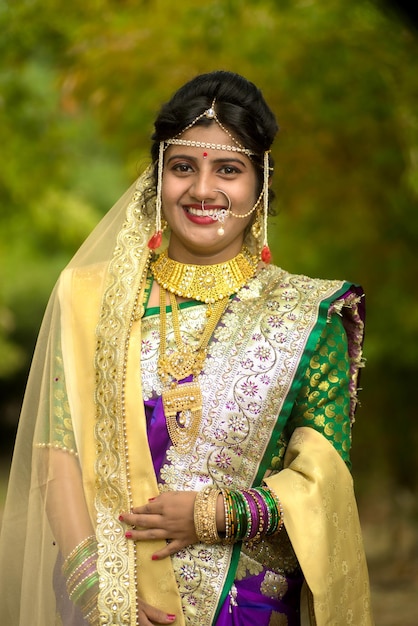 Close up di bella sposa indiana in saree tradizionale che posa all'aperto nel parco