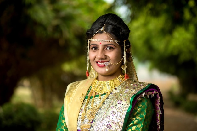 Close up di bella sposa indiana in saree tradizionale che posa all'aperto nel parco