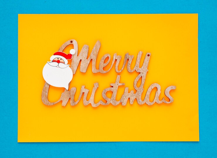 Foto close-up di buon natale scritto su carta gialla sullo sfondo blu