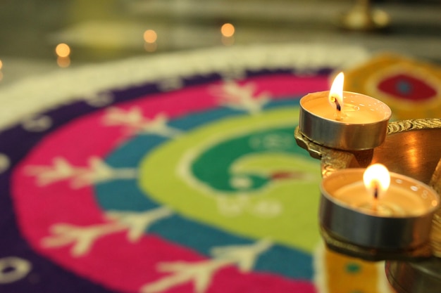 Close-up di candele illuminate contro rangoli colorati