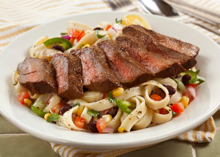 Foto close-up di carne e pasta in piatto su tavola
