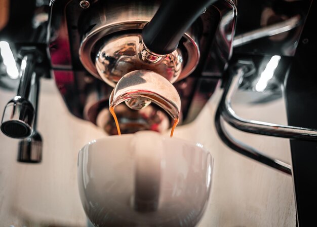 Close-up di espresso che viene versato dalla macchina del caffè in una tazza di caffè