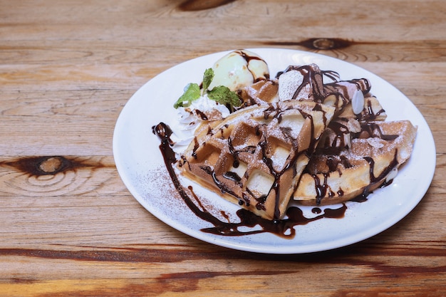 Close-up di gelato alla vaniglia con waffle sullo sfondo di un tavolo di legno