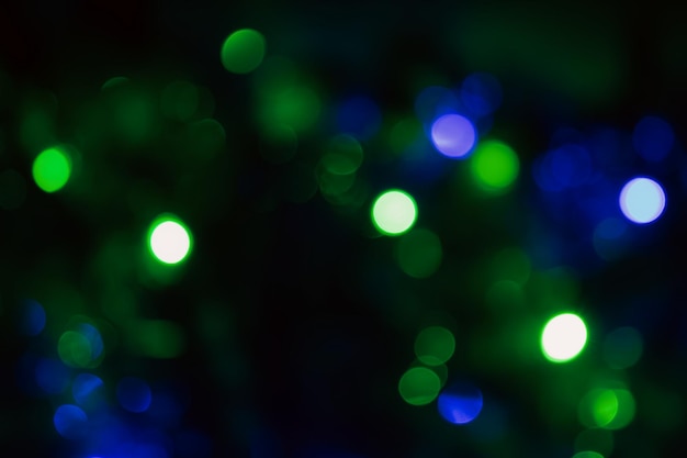 close-up di luci bokeh verdi e blu su uno sfondo scuro che evoca un'atmosfera onirica e magica