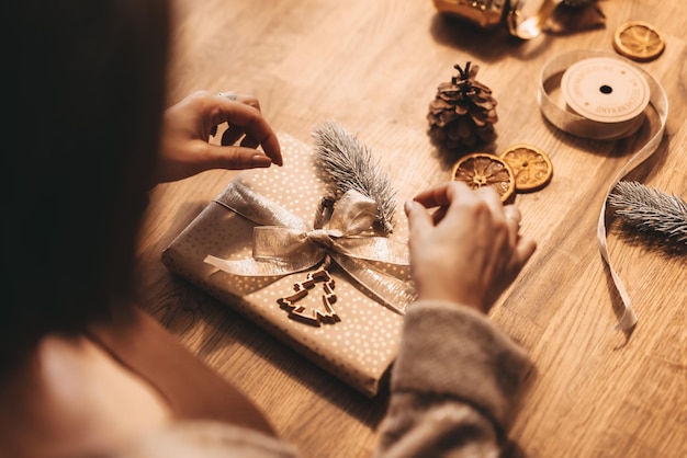 Close-up di mani che avvolgono regali per Natale decorazione elegante colori caldi vintage