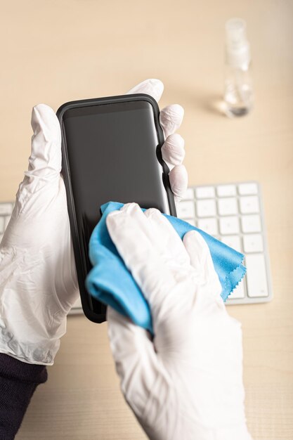 Close-up di mani che puliscono il telefono cellulare con un tovagliolo